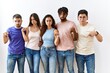 © Krakenimages.com - Group of young people standing together over isolated background pointing down looking sad and upset, indicating direction with fingers, unhappy and depressed.