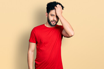 Sticker - Young arab man with beard wearing casual red t shirt surprised with hand on head for mistake, remember error. forgot, bad memory concept.