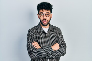 Poster - Young arab man with beard wearing glasses with arms crossed gesture afraid and shocked with surprise and amazed expression, fear and excited face.