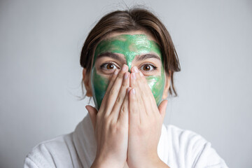 Wall Mural - Attractive young woman with a green cosmetic mask on her face.