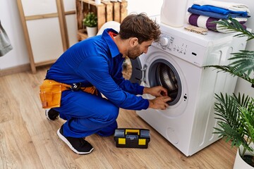 Sticker - Young hispanic man wearing handyman uniform repairing washing machine at laundry room