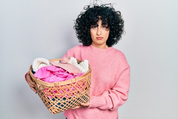 Sticker - Young middle east woman holding laundry basket relaxed with serious expression on face. simple and natural looking at the camera.