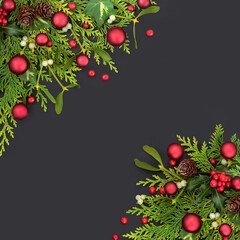 Wall Mural - Christmas background with red ball bauble decorations, winter greenery, holly, cedar, mistletoe, pine cones and ivy leaves with loose berries on grey background. Top view, flat lay, copy space.