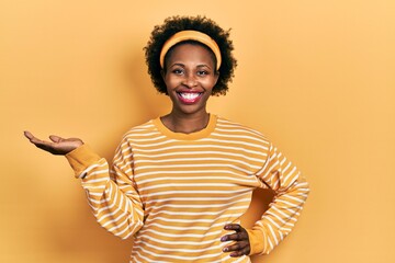 Canvas Print - Young african american woman presenting with open palms, holding something smiling with a happy and cool smile on face. showing teeth.