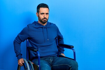 Sticker - Handsome hispanic man with beard sitting on wheelchair skeptic and nervous, frowning upset because of problem. negative person.