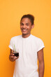 © YarikL - Portrait of a cheerful afro american guy in white t-shirt drinking a drink from a glass with a straw on yellow background