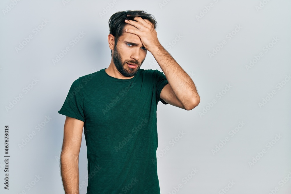 Young hispanic man wearing casual white tshirt surprised with hand on head for mistake, remember error. forgot, bad memory concept.