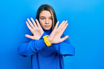 Sticker - Young brunette girl wearing turtleneck sweater rejection expression crossing arms and palms doing negative sign, angry face