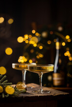 Two Glasses Of Champagne And Bottle Against Fireworks And Holiday Lights, Dark Background