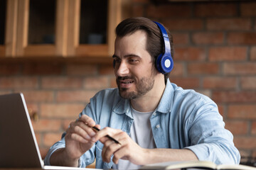 Wall Mural - virtual conversation. male remote employee in headset work from distant home office speak on corpora