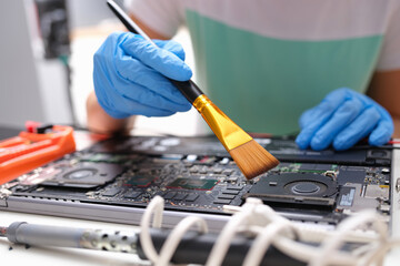 Wall Mural - Hands brush the laptop parts from dust with a brush