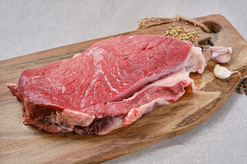 Wall Mural - Raw steak on cutting board ready to cook. Fresh cut of beef on wooden kitchen board with spices and garlic on a granite table. Selective focus