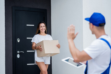 Wall Mural - Young courier delivering goods to a young woman at home