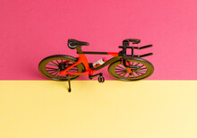Sport Is Life. A Toy Red And Black Sports Bike Stands On The Border Of A Pink And Yellow Background. Minimal Creative Idea. A Whole Day Of Cycling. Side View From Above. A Place To Copy.