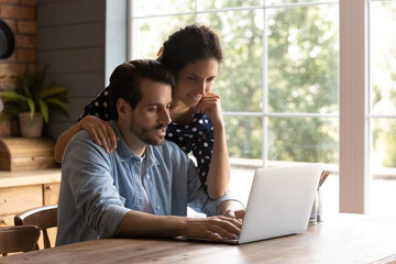 searching information. caring wife stand behind beloved husband typing on laptop keyboard hug his sh