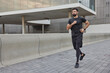 © WHstudio Leushin N - Determined bearded adult man in activewear jogs in city street covers long distance enjoys morning running exercises outdoors keeps fit and healthy muscular strength flexibility physical power