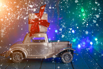 Wall Mural - Retro car with a gift on the roof against the background of Christmas lights.