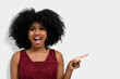 portrait of a dark-skinned girl with afro haircut, points with her front fingers, shows blank space for her promotion