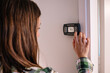 woman lowers the temperature thermostat climate control home to save energy