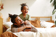 © JenkoAtaman - Happy afro american family father and cute little son relaxing at home in bed
