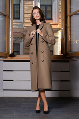 Wall Mural - A female model posing shows off a stylish modern beige coat. A fashionable women's clothing store.