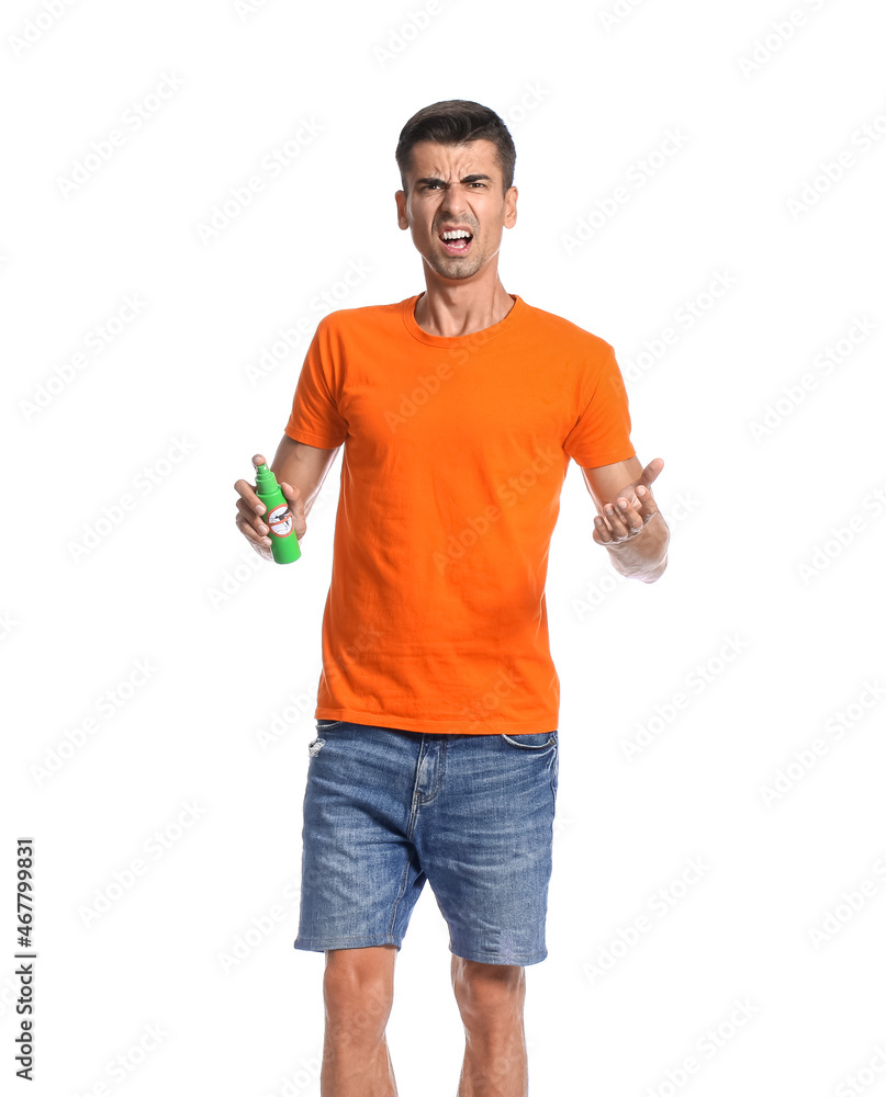Angry young man with mosquito repellent on white background