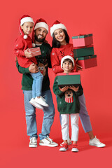 Wall Mural - Happy family in Santa hats with Christmas gifts on red background