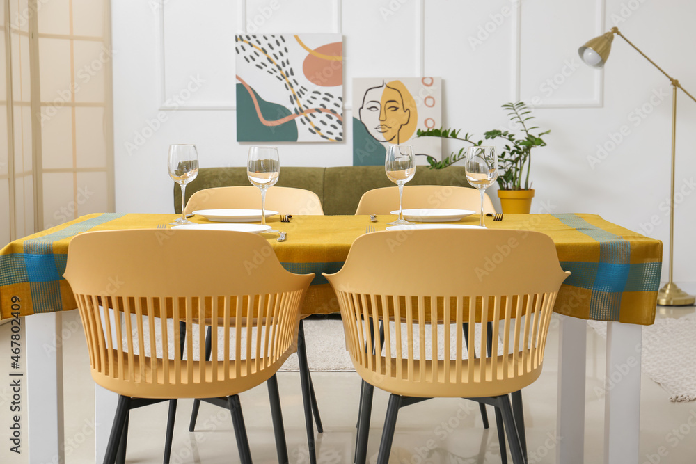 Dining table with bright cloth and chairs in modern room