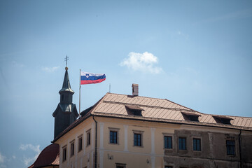 Flag of Slovenia waiving in the air with a sunny sky background on the Ljubljana Castle. Slovenia, one of the former constituents of Yugoslavia, is a Central European country...