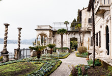 Garden With Palm Trees And Columns Near Villa Monastero. Lake Como, Italy