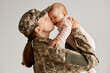 Indoor shot of happy emotional soldier woman returning home from army, lifting infant daughter and kissing her, greeting after returning home from a tour of duty overseas.