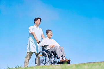 介護士と車椅子に乗る高齢者　屋外