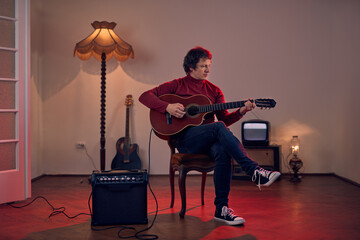 Wall Mural - Male musician playing acoustic guitar on the amplifier in retro vintage room.