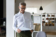 © Westend61 - Smiling businessman with hand in pocket reading document at office