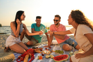 Canvas Print - Group of friends having picnic outdoors at sunset