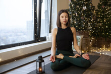 young woman meditation and doing yoga fitness exercise  in the Christmas interior  at home. home fitness, activewear. Healthy and sport lifestyle. Christmas holidays
