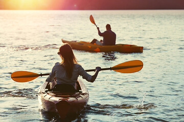 Wall Mural - Couple kayaking on river in evening, back view. Summer activity