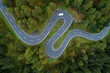 © Westend61 - Drone view of single car driving along winding Maloja Pass road
