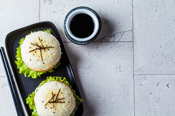 Wall Mural - Rice burger with salmon cutlet, avocado and soy sauce, top view.