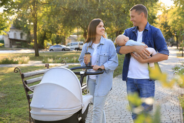 Canvas Print - Happy parents walking with their baby in park on sunny day