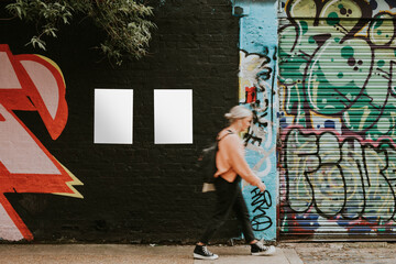 Woman walking past street art mural and blank posters