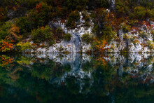 Turquoise Blue Mountain Lake With Reflections Of Cliffs And Forest In Intense Fall Colors