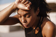 © Drobot Dean - Black sportswoman wiping her forehead while working out on parking