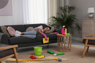 Sticker - Tired young woman sleeping on sofa and cleaning supplies in living room