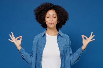 Wall Mural - Young black woman in casual clothes shirt white t-shirt hold spreading hands in yoga om aum gesture relax meditate try calm down isolated on plain dark blue background studio People lifestyle concept