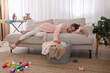 © New Africa - Tired young mother sleeping on sofa in messy living room