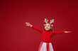 happy little girl in reindeer antlers on red background