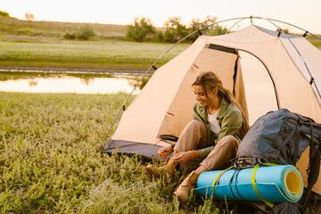 white woman tying her shoelaces while sitting in tent during camping
