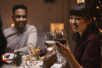 Wall Mural - holidays, party and celebration concept - multiethnic group of happy friends having christmas dinner at home and drinking wine