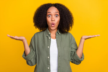 Photo of cool brunette young lady hold empty space wear khaki shirt jeans sneakers isolated on yellow color background